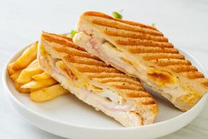 Ham and cheese sandwich with egg and fries photo