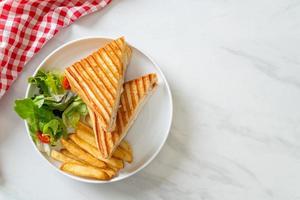 Ham and cheese sandwich with egg and fries photo