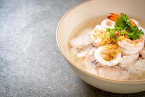 Porridge or boiled rice soup with seafood of shrimp, squid, and fish in a bowl photo
