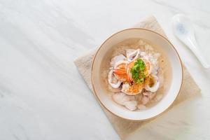 Porridge or boiled rice soup with seafood of shrimp, squid, and fish in a bowl photo