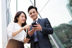 Two Asian business people using smartphone and talking together photo