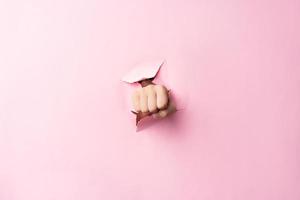 The image of the woman holding her fist through the torn paper shows anger photo