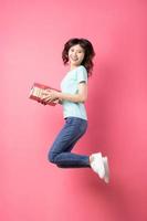 Woman holding gift box jumping up with cheerful expression on background photo