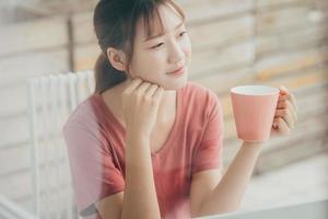 Mujer asiática beber café en su balcón por la mañana foto