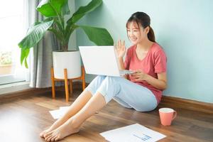 Asian woman sitting on the floor while she working from home photo