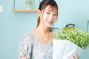 una joven mujer asiática sosteniendo flores en su habitación