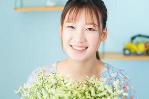 una joven mujer asiática sosteniendo flores en su habitación