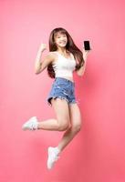 Image of young Asian girl jumping on pink background photo