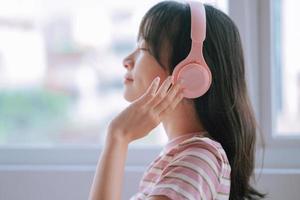 Young Asian woman using wireless headphones to listen music photo