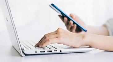 Asian woman using laptop and smartphone photo