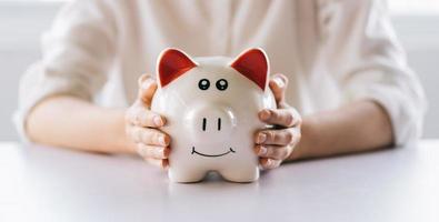 Woman hand holding piggy bank on table, save money and financial investment photo