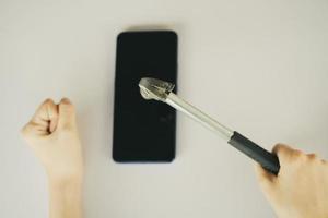 Asian woman using hammer to break her smartphone photo