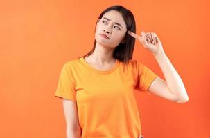 Image of young Asian woman wearing orange t-shirt on orange background