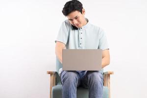 Handsome man with laptop sitting on sofa listening to the phone and working photo