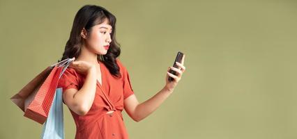 Asian woman is carrying shopping bag and staring at her phone photo