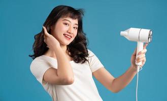 A photo of a beautiful young Asian girl drying her hair