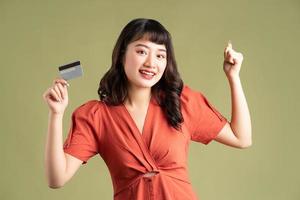 Mujer asiática sosteniendo una tarjeta bancaria y mostrando emoción de victoria