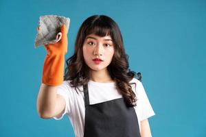 A photo of an Asian woman in an apron and gloves preparing for the cleaning job