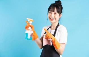 Ama de casa asiática lleva guantes naranjas y sostiene un chorro de agua en la mano foto