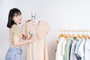 Hermosa mujer asiática aplanar su vestido con la plancha de vapor foto