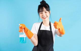 Asian housewife is wearing orange gloves and holding a spray of water in her hand photo