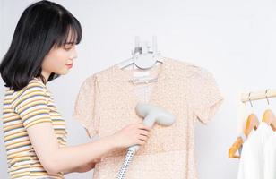 Beautiful Asian woman flattening her dress with the steam iron photo