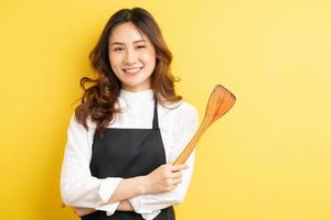 Housewife beauty holding rice spoon and smile isolated on yellow background photo