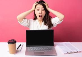 Young Asian businesswoman sitting working with expression on background photo