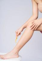 joven asiática está usando una navaja para afeitarse las piernas foto