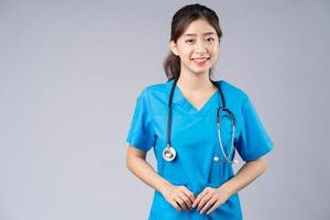 Imagen de la joven doctora asiática vistiendo uniforme azul sobre fondo gris foto
