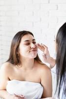 two beautiful women applying facial cream doing spa procedures photo