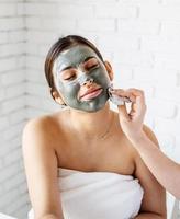 Portrait of a beautiful woman applying facial mask doing spa procedures photo