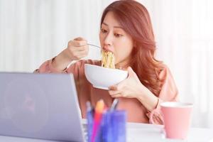 Asian businesswoman has to eat noodles while working photo