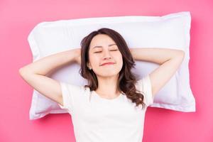 mujer asiática durmiendo sobre fondo rosa foto