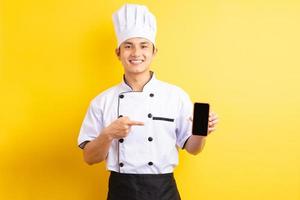 The Asian male chef was pointing his finger at the cell phone he was holding photo