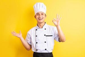 Image of Asian male chef on yellow background photo