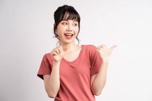 Joven mujer asiática posando sobre fondo blanco, usando el dedo para señalar y mostrar, gesto con la mano foto