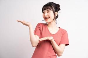 Joven mujer asiática posando sobre fondo blanco, usando el dedo para señalar y mostrar, gesto con la mano foto
