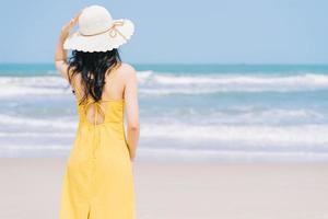 Joven mujer asiática disfrutando de las vacaciones de verano en la playa. foto