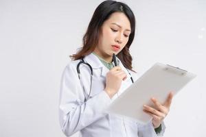 Beautiful Asian female doctor reading the document with a thoughtful expression photo