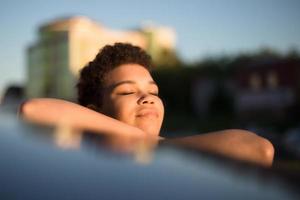 Beautiful African American woman with short hair near the car, lifestyle photo