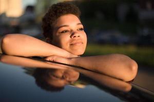 Feliz y hermosa mujer afroamericana con pelo corto cerca del coche foto