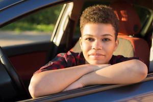 Feliz y hermosa mujer afroamericana con pelo corto en un coche, estilo de vida