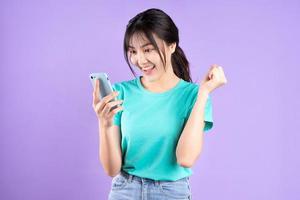 Young Asian girl in cyan shirt on purple background