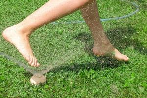 A child runs through the wet grass in hot summer photo