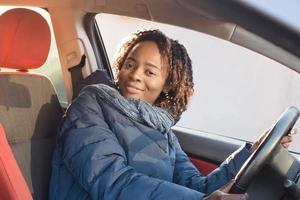 Happy african-american woman in a car driving, autumn-winter photo