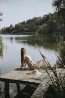 Relaxing young woman on wooden pier at the lake photo