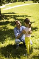 Father with daughter having fun on the grass at the park photo