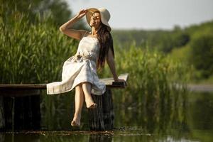 Relaxing young woman on wooden pier at the lake photo