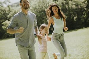 Happy young family with cute little daughter running in the park on a sunny day photo